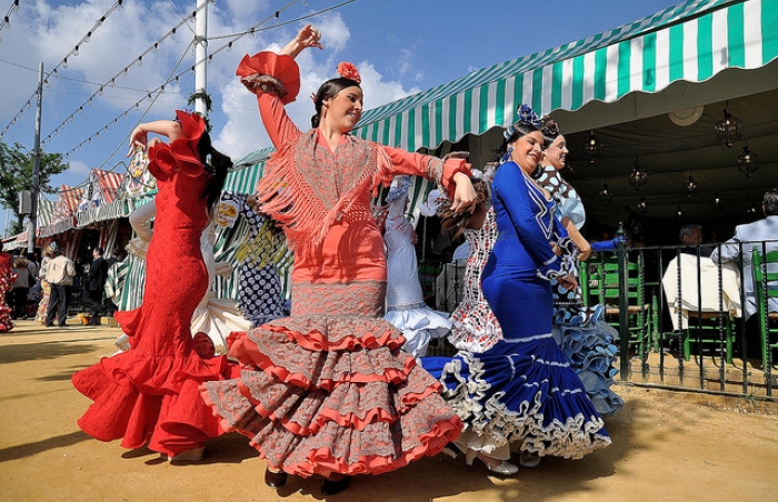 Women dressed in typical Flamenca dresses, dancing Sevillanas